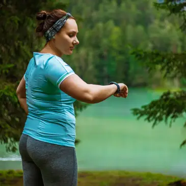 woman walking looking at smart watch while in nature